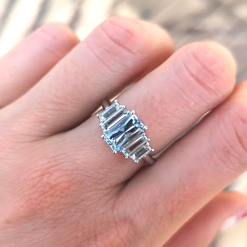 Close-up of Marine Deco Ring with aquamarine center stone and side stones on middle finger, perfect for March birthdays