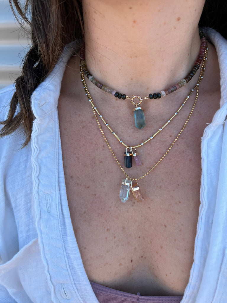 Lico Jewelry's Fluorite Crystal Pendant, handcrafted in Montreal, featuring a genuine fluorite crystal in shades of green, lilac and a hint of brown, paired with other necklaces for a layered look.