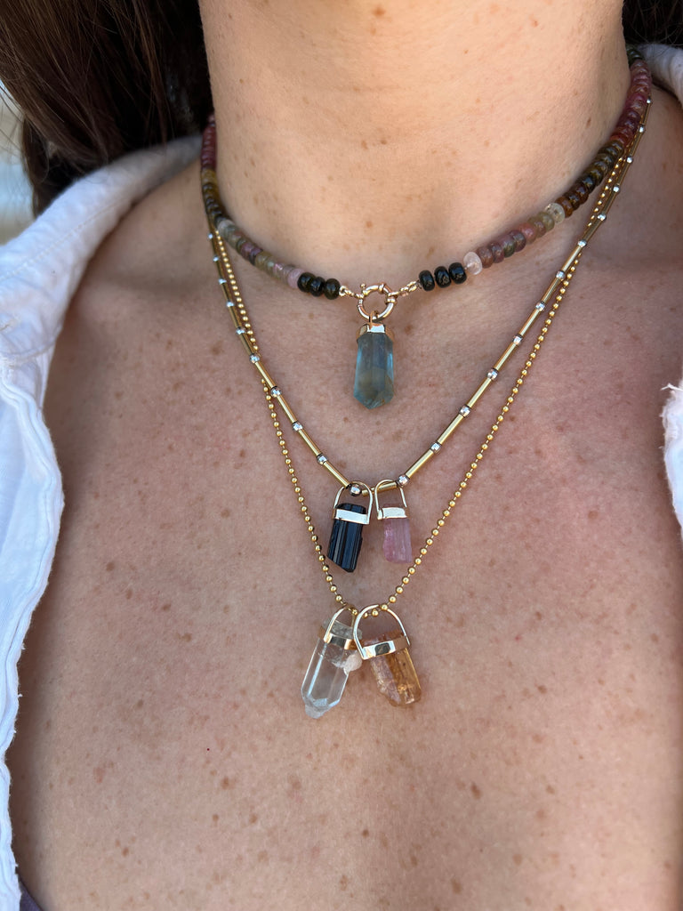 Woman wearing stylish necklaces, including a black tourmaline rough crystal pendant from Lico Jewelry