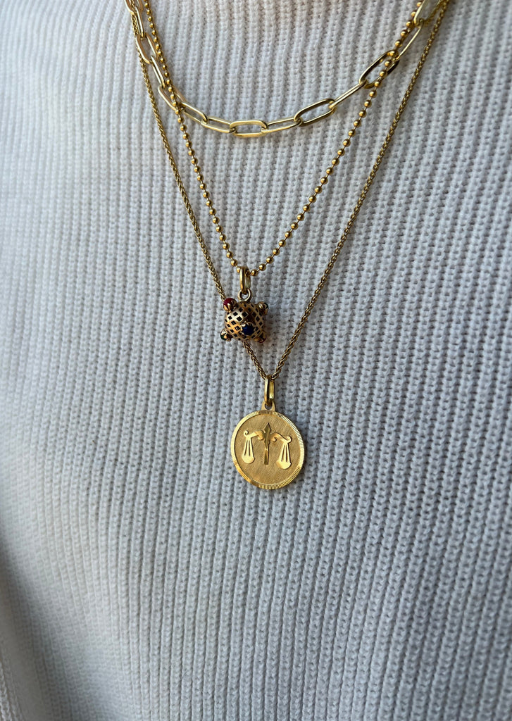 Beautiful 18K yellow gold Libra medallion necklace from Lico Jewelry, worn with other gold necklaces and charms.