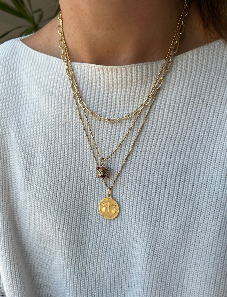 Lico Jewelry's stunning 18K yellow gold Libra medallion pendant, paired with other gold necklaces and charms