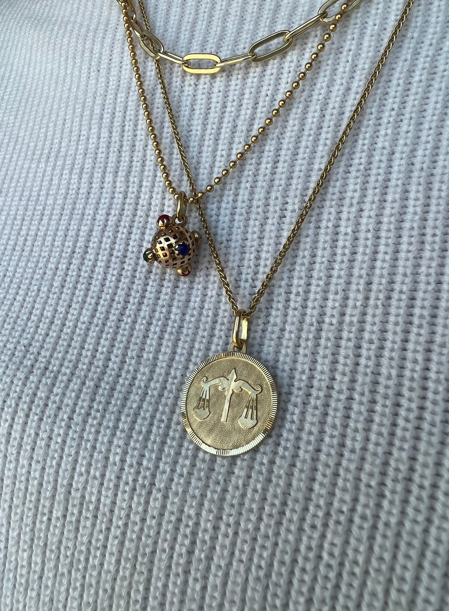 Lico Jewelry's stunning 18K yellow gold Libra medallion pendant, paired with other gold necklaces and charms