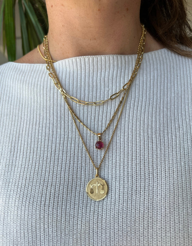 Lico Jewelry's vintage 18K Libra medallion pendant, layered with other gold necklaces and chains.