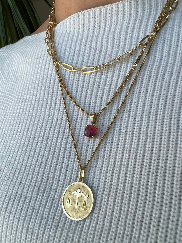 Vintage 18K Libra medallion necklace from Lico Jewelry in Montreal, paired with other gold necklaces and charms.