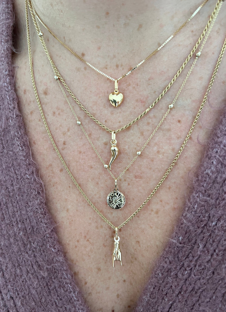 Woman wearing a variety of stylish necklaces, including the Cornicello charm by Lico Jewelry.