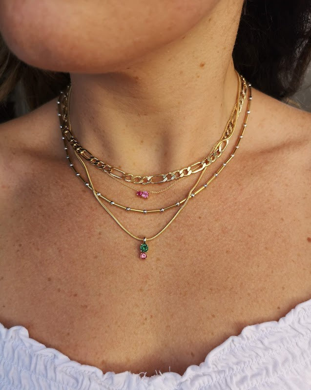 Model wearing the Spring mix 2 pendant by Lico Jewelry layered with other necklaces and pendants. She is wearing a white shirt and the pendant features genuine green and pink tourmaline stones in 14k yellow gold on a rolo chain