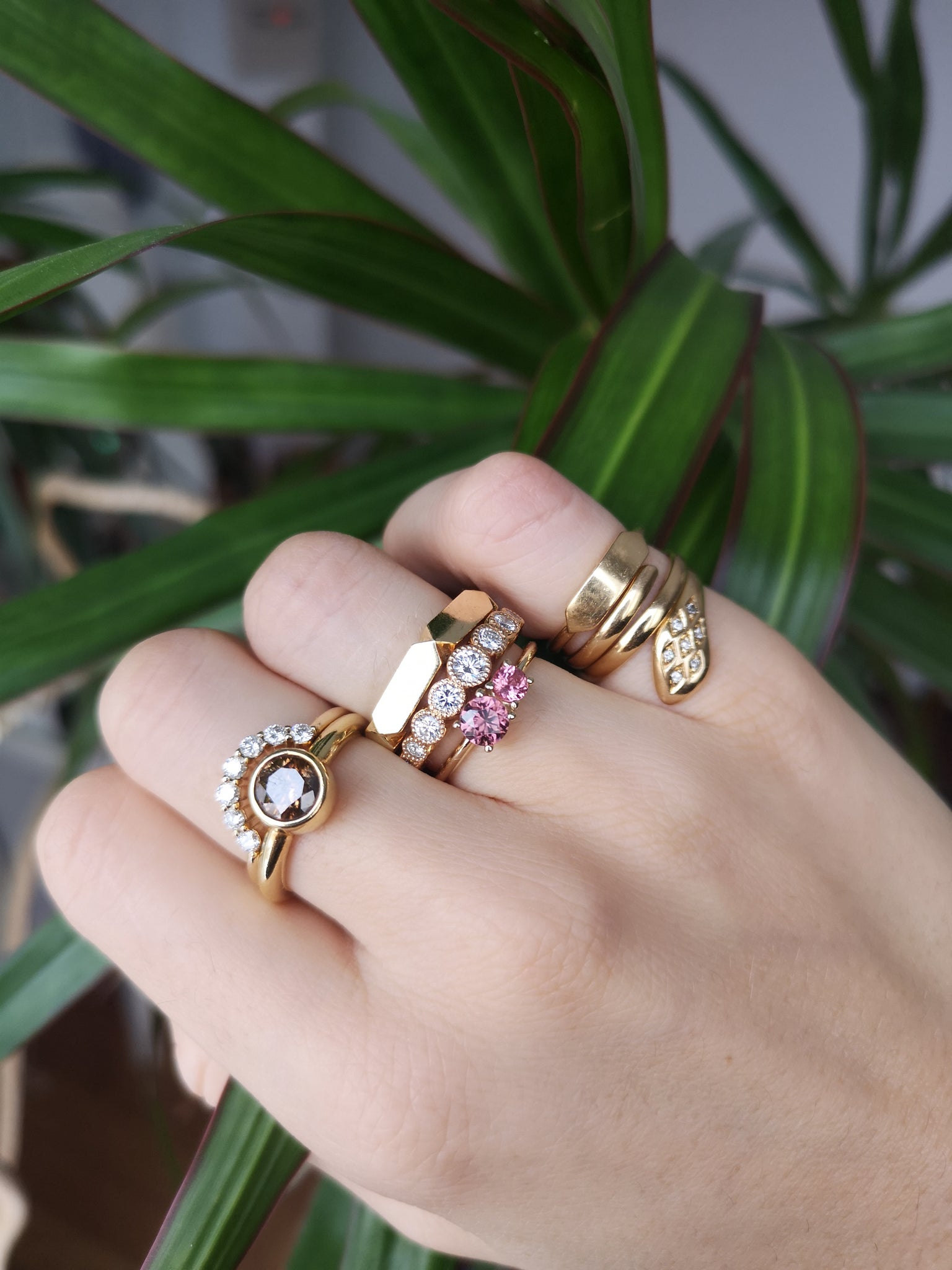Mix and match the Muted Rose ring from Lico Jewelry with other rings for a personalized look. Featuring a natural pink-brown zircon and pink spinel set in 14k yellow gold. December and August birthstones. Available now from Lico Jewelry in Montreal with green plant in background