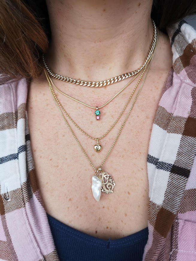 Model wearing the Spring mix 2 pendant by Lico Jewelry layered with other necklaces and pendants. She is wearing a plaid shirt and the pendant features genuine green and pink tourmaline stones in 14k yellow gold on a rolo chain.