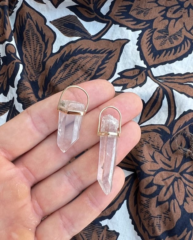 Lico Jewelry Clear Quartz Crystal Pendants, set in 14K yellow gold, paired on a woman's hand. Montreal-based company.