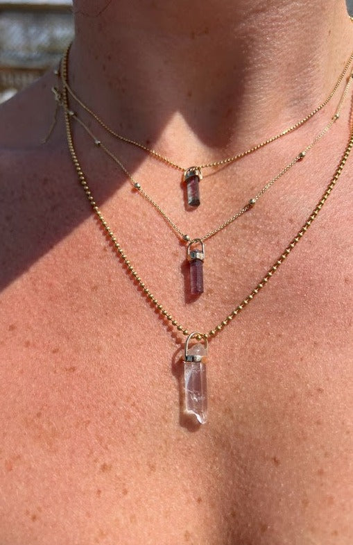 woman wearing a clear quartz crystal pendant from Lico Jewelry, a Montreal-based company, paired with other beautiful necklaces.