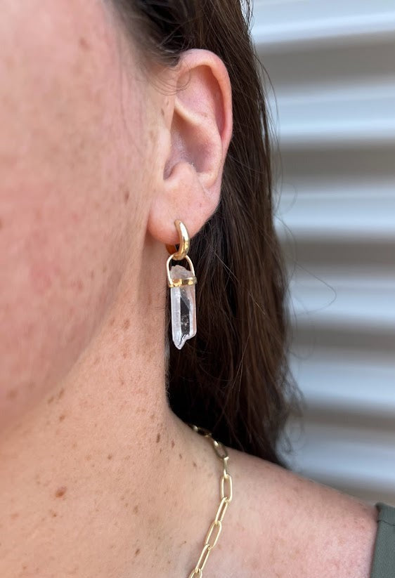 Lico Jewelry Clear Quartz Crystal Pendant, set in 14K yellow gold, worn as an earring on a woman model. Montreal-based company.