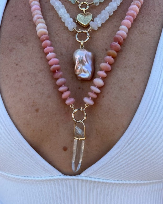 woman wearing a clear quartz crystal pendant from Lico Jewelry, a Montreal-based company, paired with other beautiful necklaces.