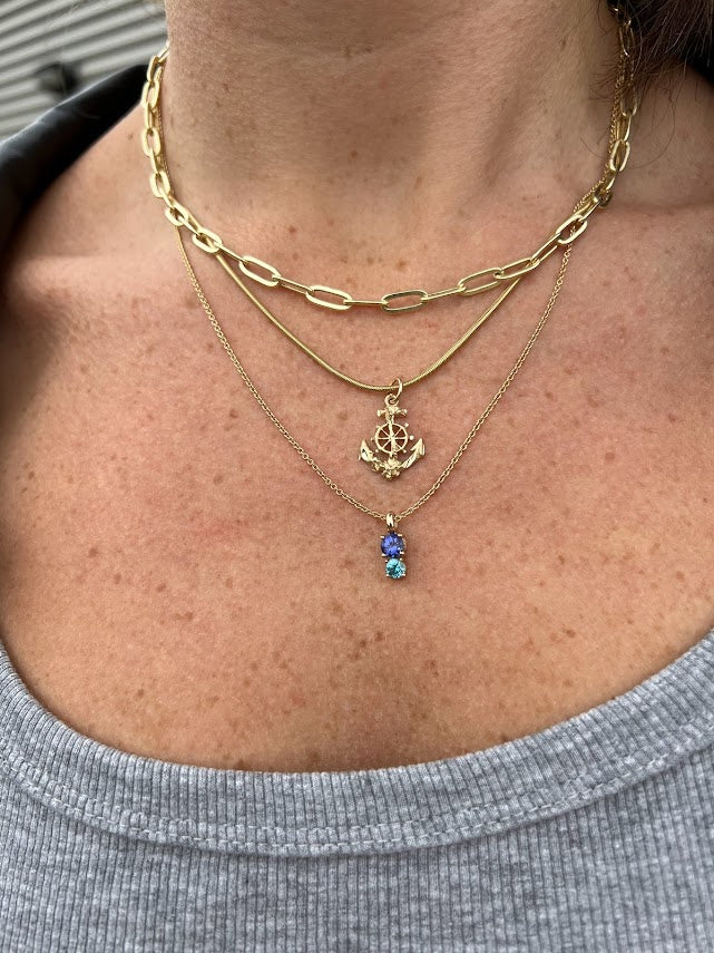A woman wearing Lico Jewelry's Deep Sea pendant paired with other beautiful necklaces, based out of Montreal.