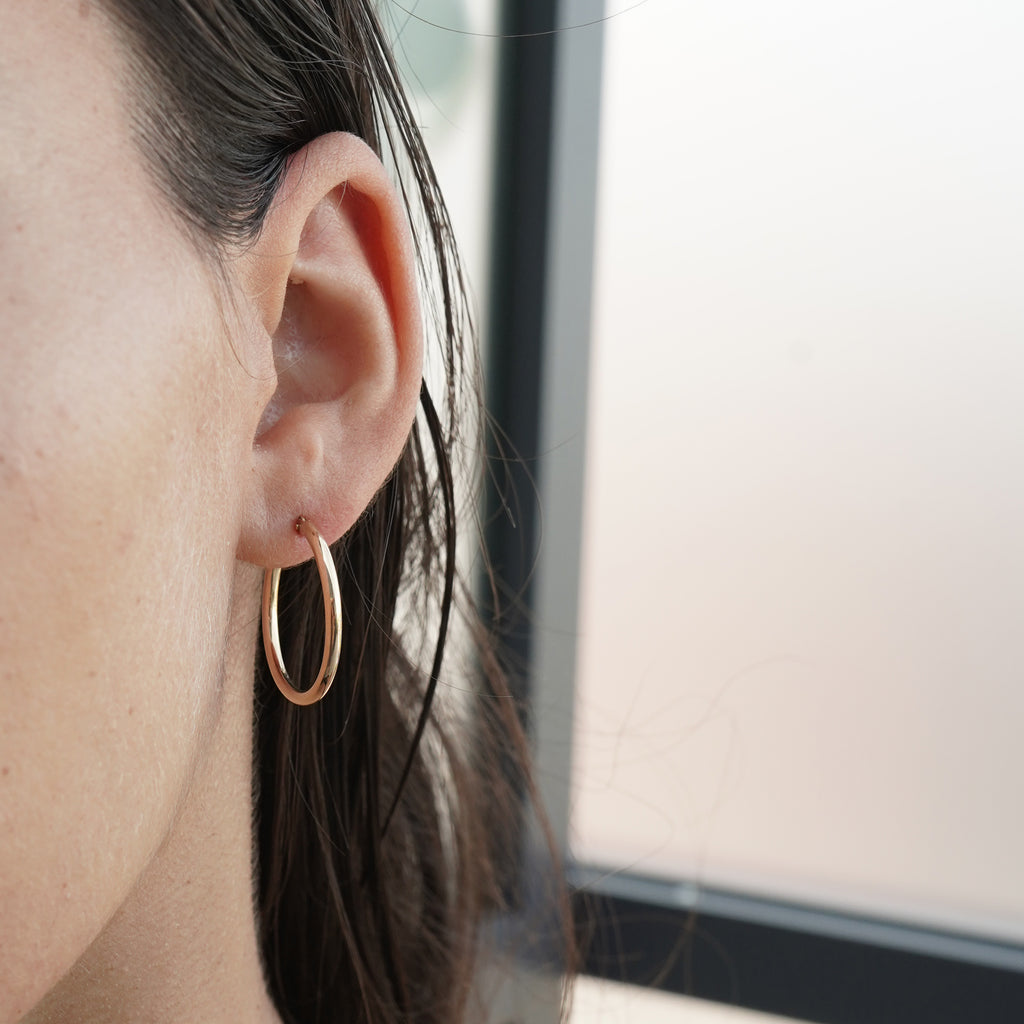 14K yellow gold earrings from Lico Jewelry, featuring a model wearing the 20 mm hoops and show the details of the earring"