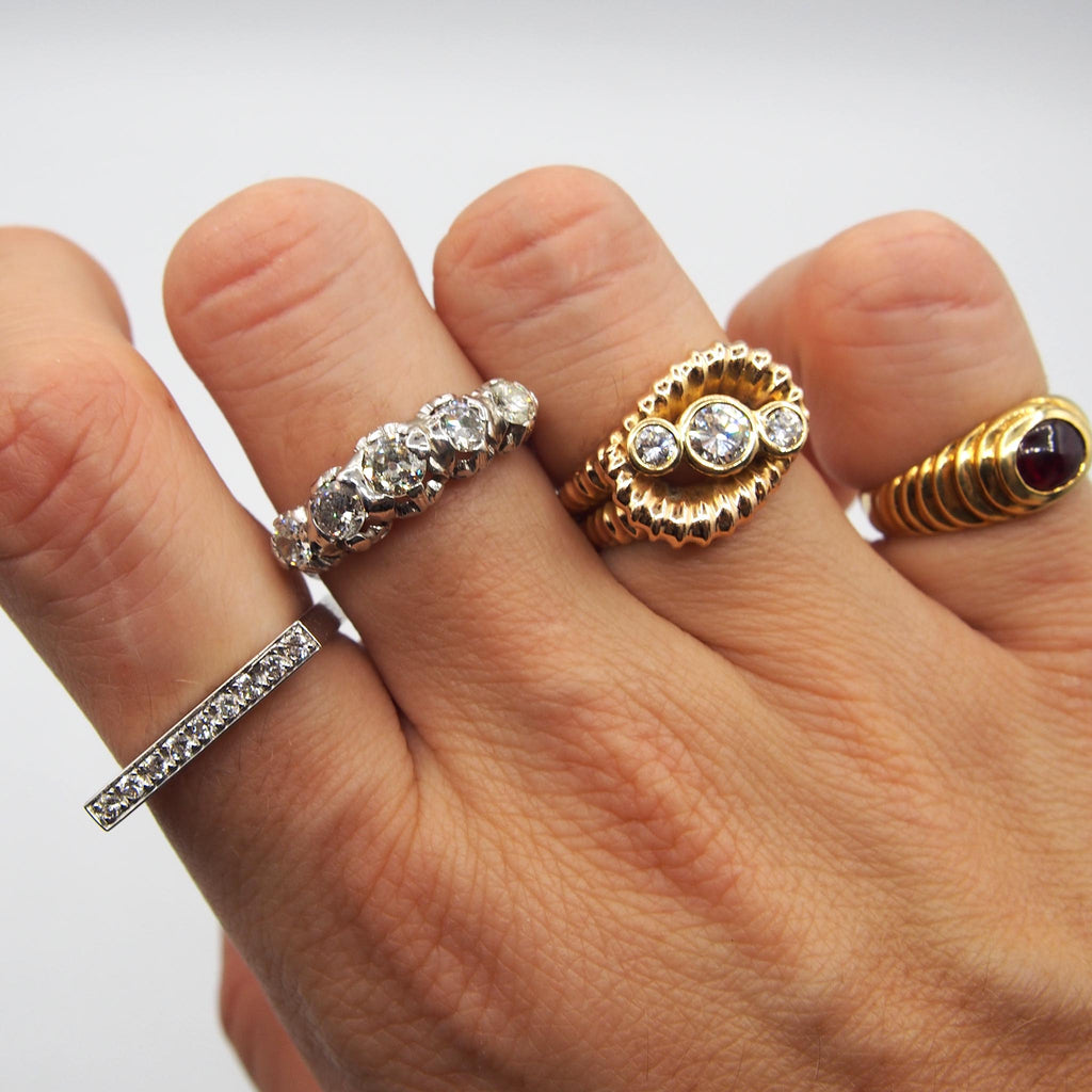 Hand model showcasing four rings on each finger, including the vintage 18K cabochon garnet ring from Lico Jewelry