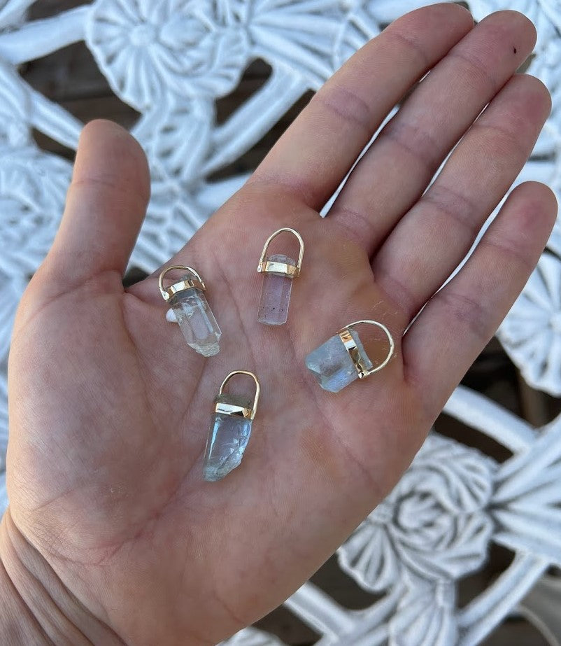 Aquamarine crystal pendants in 14K yellow gold from Lico Jewelry, laid out on a hand for display, showcasing the natural variations in the crystals
