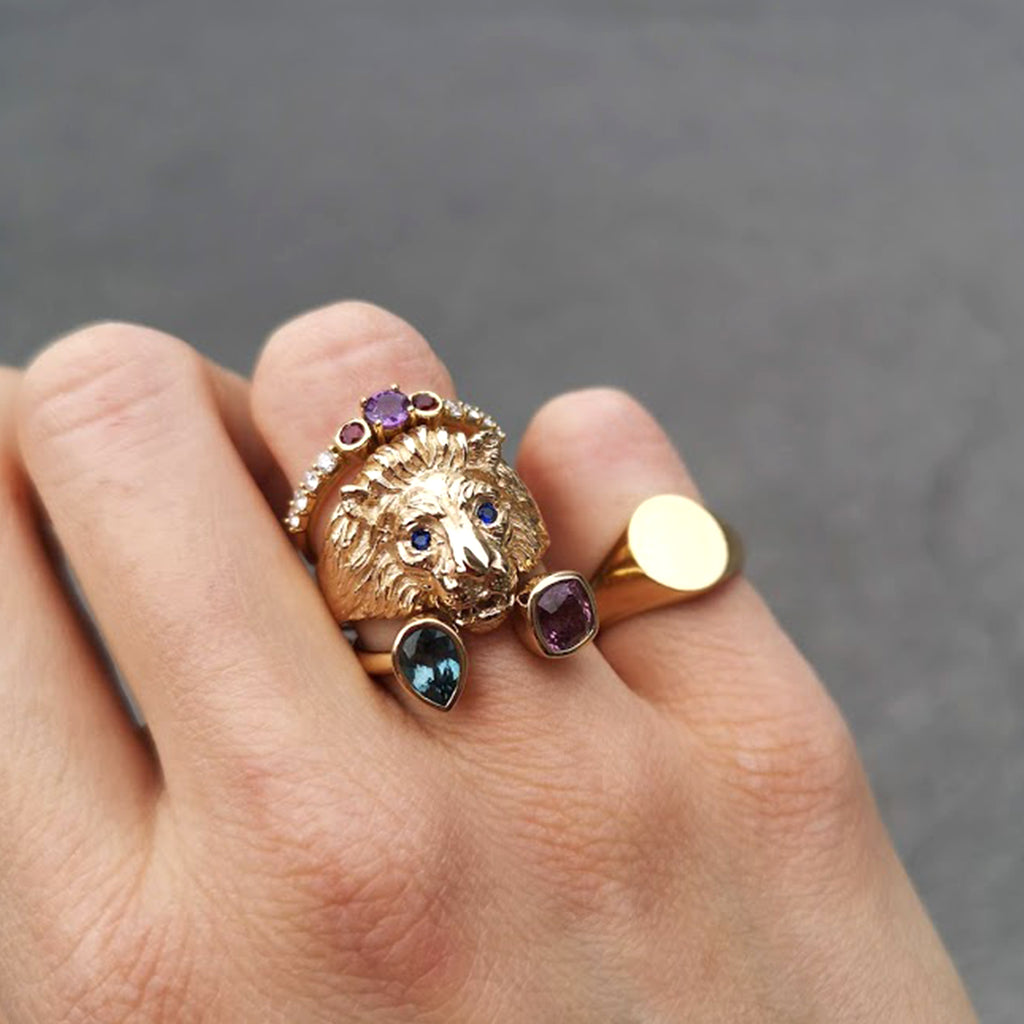 A woman's hand wearing a Lico Jewelry's Cuor di Leone ring on the engagement finger with multiple other rings, based out of Montreal.