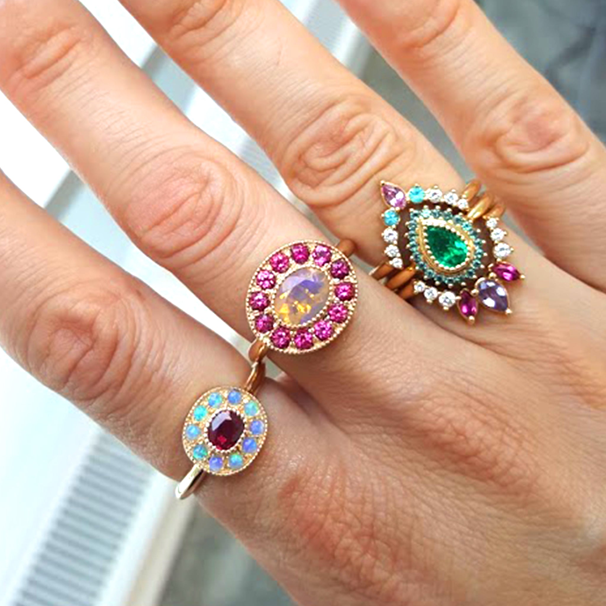 Woman's hand adorned with three Lico rings, one being the one-of-a-kind Ruby halo ring with mini Australian opals, retro-antique inspired design by Lico Jewelry, set in solid 14k yellow gold.